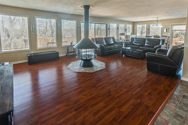 unfurnished living room featuring wood finished floors, a wood stove, and baseboards