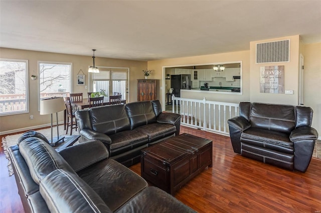 living room featuring wood finished floors, visible vents, and baseboards