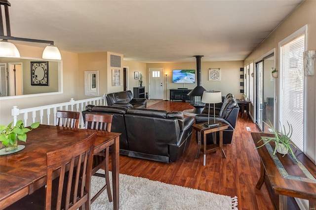 living area with a wood stove, visible vents, and dark wood-style flooring