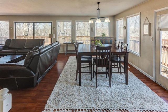 dining area with dark wood-style floors, baseboards, and an inviting chandelier