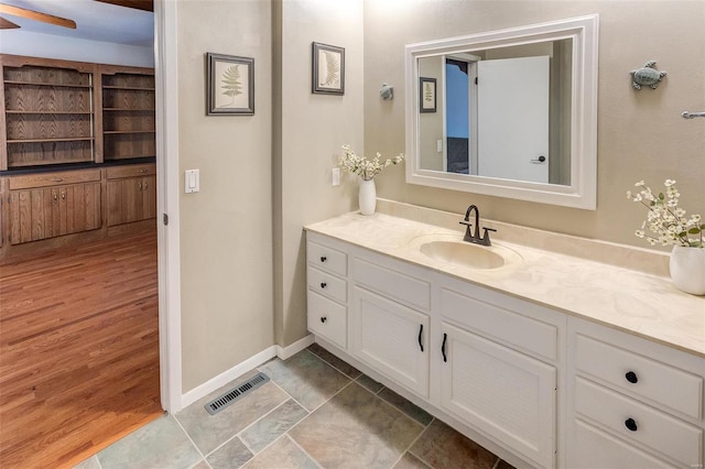 bathroom featuring visible vents, vanity, baseboards, and wood finished floors