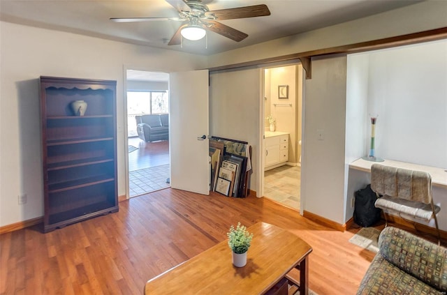 living area featuring light wood-style floors, ceiling fan, and baseboards