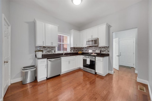 kitchen featuring dark countertops, visible vents, stainless steel appliances, and a sink