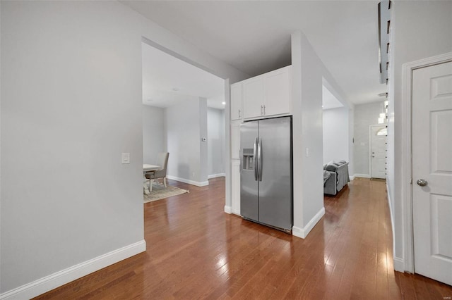 kitchen featuring baseboards, hardwood / wood-style flooring, white cabinetry, and stainless steel fridge with ice dispenser