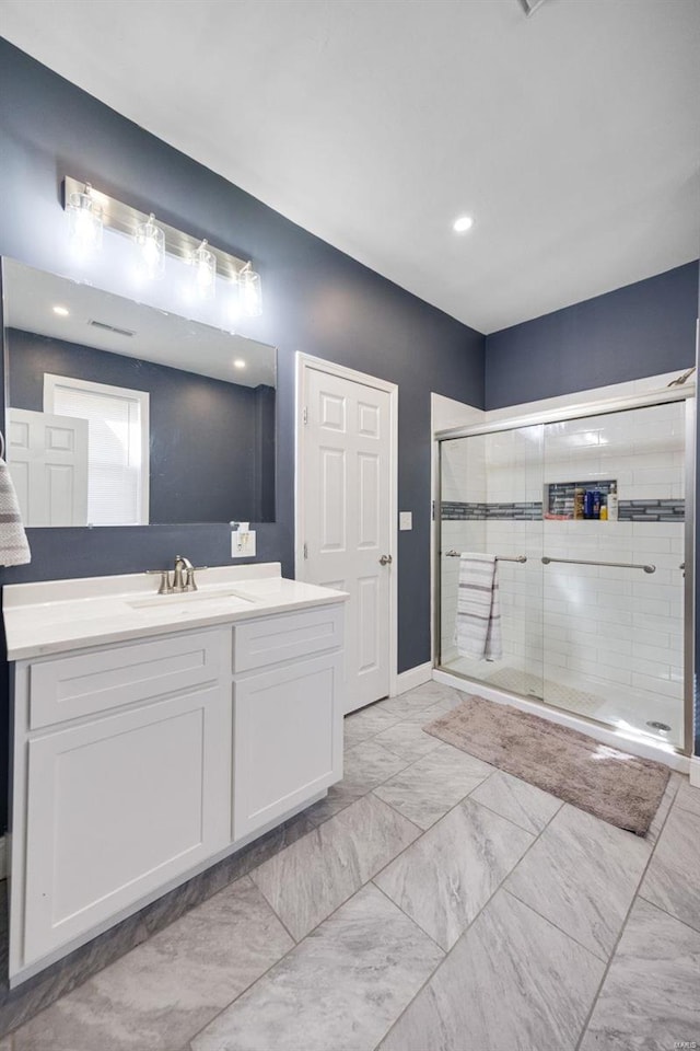 full bathroom featuring marble finish floor, vanity, and a stall shower