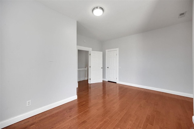 unfurnished room featuring wood finished floors, visible vents, and baseboards