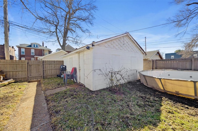 exterior space featuring a fenced backyard, a fenced in pool, and an outbuilding