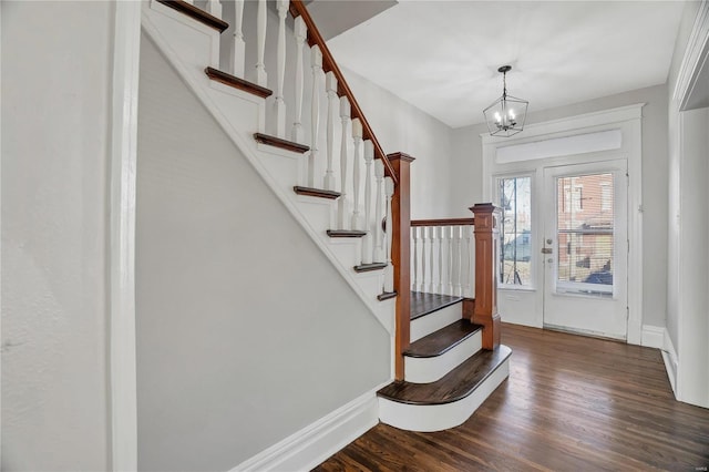 entrance foyer featuring dark wood-style floors, a chandelier, stairway, and baseboards