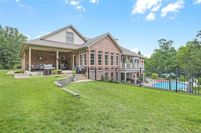 rear view of house featuring brick siding, fence, a yard, a fenced in pool, and a patio area