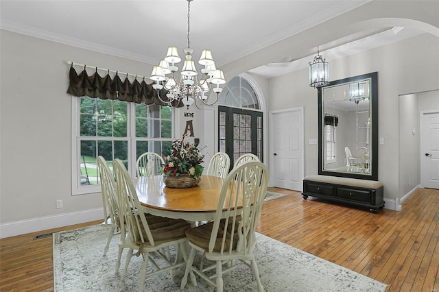 dining area featuring a chandelier, arched walkways, baseboards, hardwood / wood-style floors, and crown molding