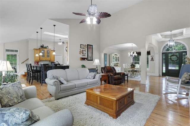 living room featuring a healthy amount of sunlight, light wood-style floors, arched walkways, and ceiling fan with notable chandelier