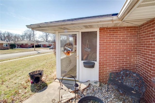 entrance to property featuring a yard and brick siding