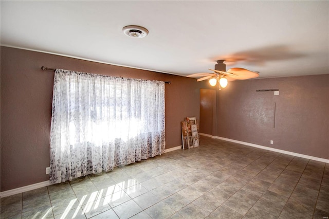 spare room featuring ceiling fan and baseboards