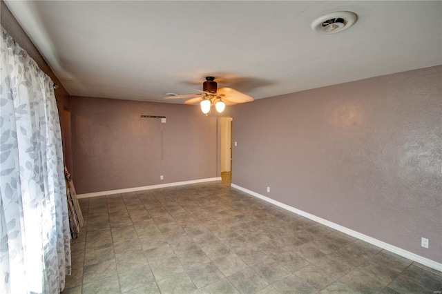 empty room featuring ceiling fan and baseboards