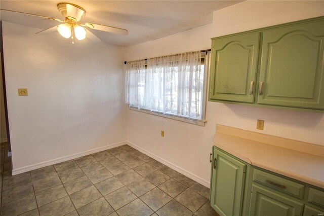 unfurnished dining area with a ceiling fan, dark tile patterned floors, and baseboards