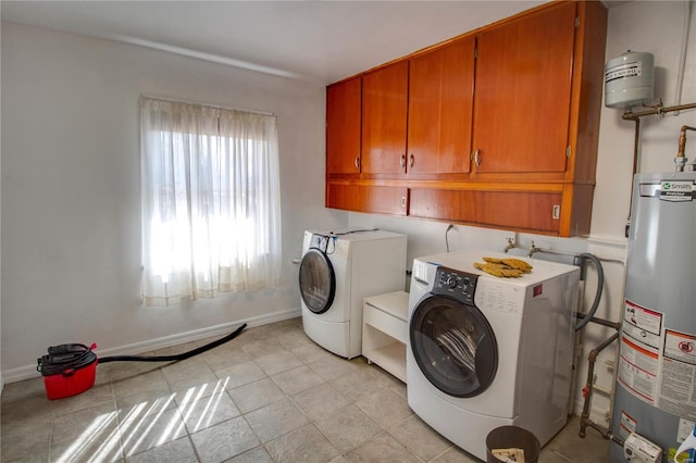 laundry room with light tile patterned flooring, gas water heater, baseboards, cabinet space, and washing machine and clothes dryer