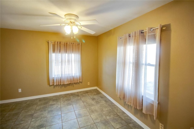 tiled empty room featuring baseboards and a ceiling fan