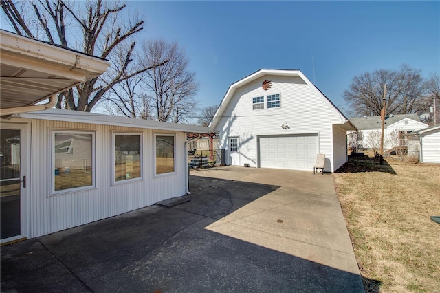 view of side of property with a garage, a yard, driveway, and a gambrel roof