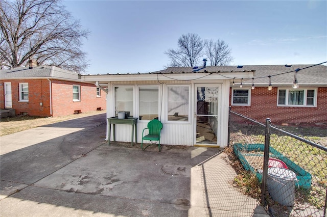 rear view of property featuring roof with shingles, fence, and brick siding