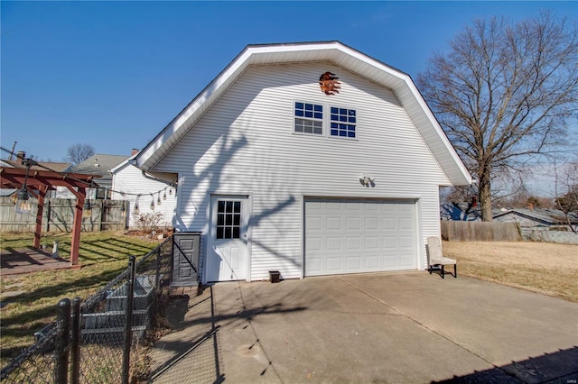 view of side of home with an attached garage, fence, and a gambrel roof