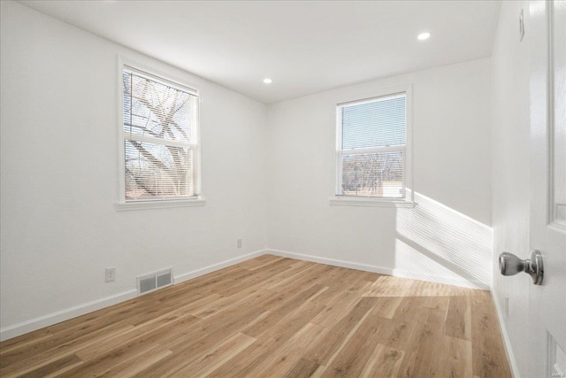 empty room featuring light wood-type flooring, visible vents, plenty of natural light, and baseboards