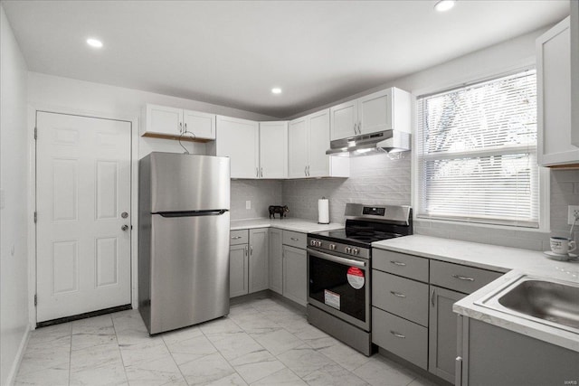 kitchen with gray cabinetry, marble finish floor, appliances with stainless steel finishes, and under cabinet range hood