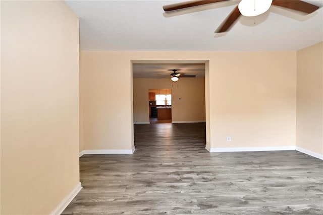 unfurnished room featuring ceiling fan, baseboards, and wood finished floors