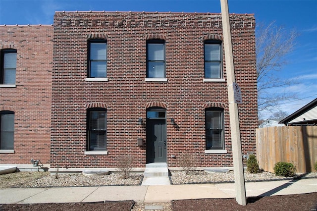 view of front facade with brick siding and fence