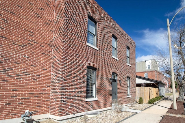 view of property exterior with brick siding and fence