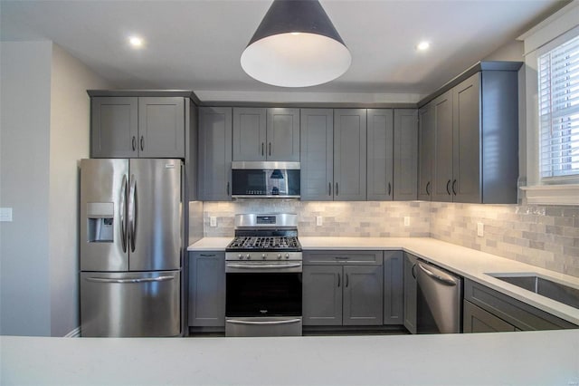 kitchen featuring recessed lighting, gray cabinetry, light countertops, appliances with stainless steel finishes, and decorative backsplash