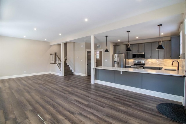 kitchen featuring stainless steel appliances, gray cabinets, light countertops, backsplash, and a sink