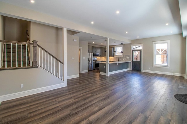 unfurnished living room with recessed lighting, dark wood finished floors, stairway, and baseboards