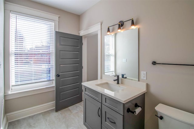 bathroom with toilet, vanity, and baseboards