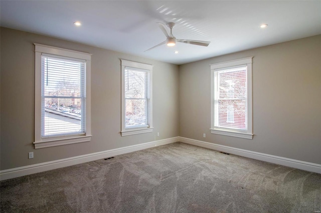 carpeted spare room with a ceiling fan, a wealth of natural light, and baseboards