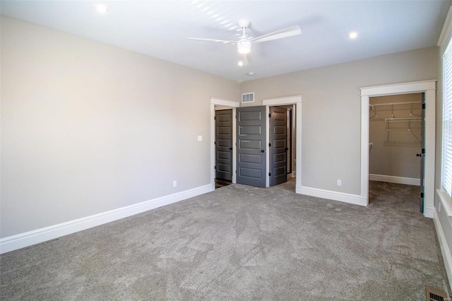 unfurnished bedroom with a spacious closet, visible vents, and baseboards