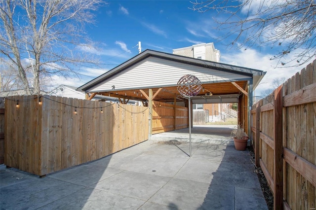 view of patio featuring a carport, concrete driveway, an exterior structure, and an outdoor structure