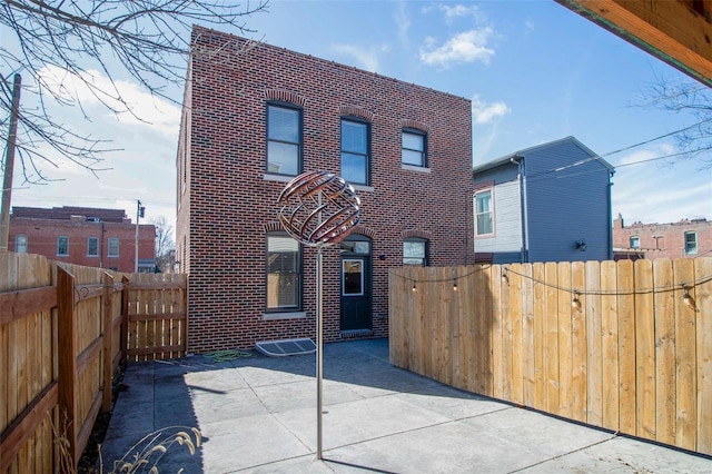 exterior space with a patio, brick siding, and a fenced backyard