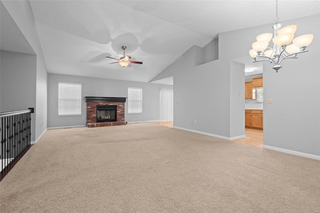 unfurnished living room with light carpet, a brick fireplace, vaulted ceiling, and ceiling fan with notable chandelier