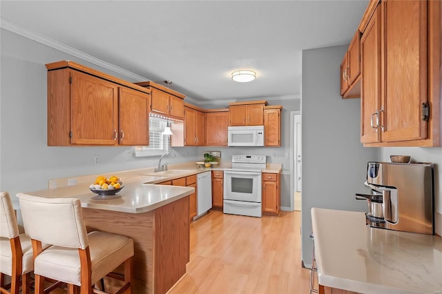 kitchen with light countertops, ornamental molding, a sink, white appliances, and a peninsula