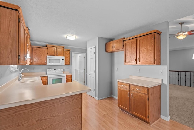 kitchen featuring light countertops, brown cabinetry, a sink, white appliances, and a peninsula