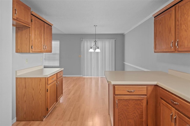 kitchen with light wood-style floors, brown cabinetry, light countertops, and hanging light fixtures