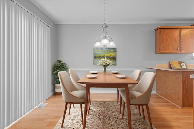 dining space featuring light wood-style floors, visible vents, and crown molding