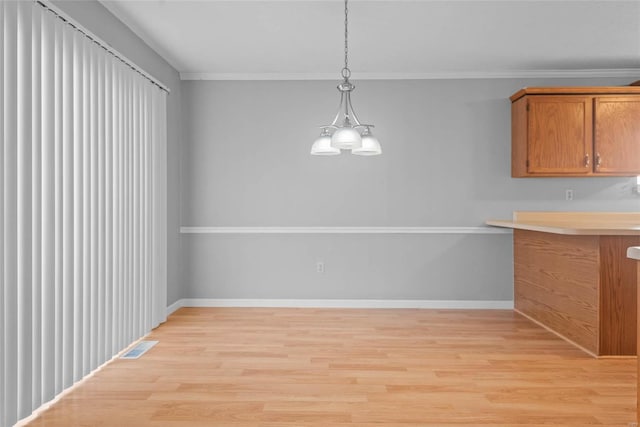 unfurnished dining area featuring visible vents, ornamental molding, light wood-style flooring, and baseboards