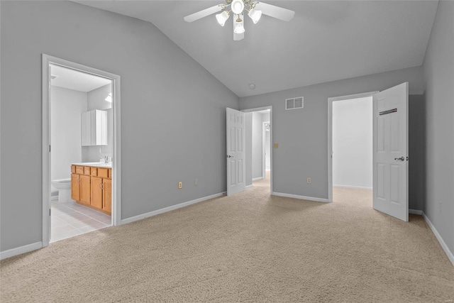 unfurnished bedroom featuring visible vents, vaulted ceiling, light carpet, and baseboards