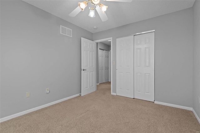 unfurnished bedroom featuring light carpet, baseboards, visible vents, ceiling fan, and a closet