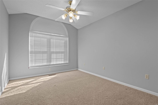 spare room with vaulted ceiling, carpet flooring, ceiling fan, and baseboards