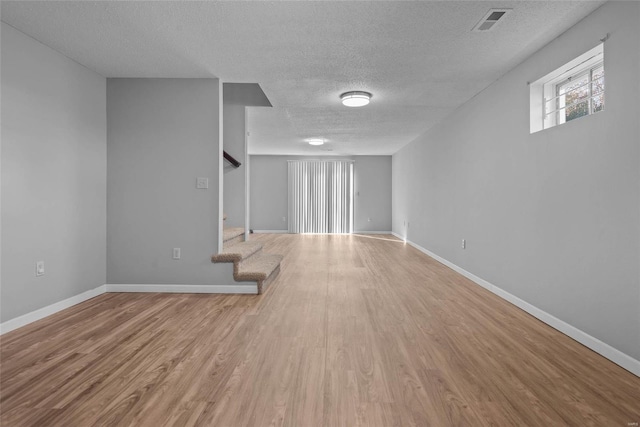 basement featuring stairs, wood finished floors, visible vents, and baseboards