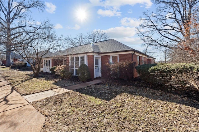 view of home's exterior with a shingled roof and brick siding