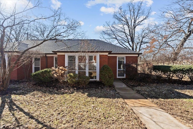 view of front facade featuring a shingled roof and brick siding