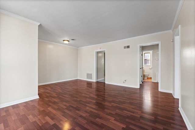 empty room with baseboards, crown molding, visible vents, and wood finished floors